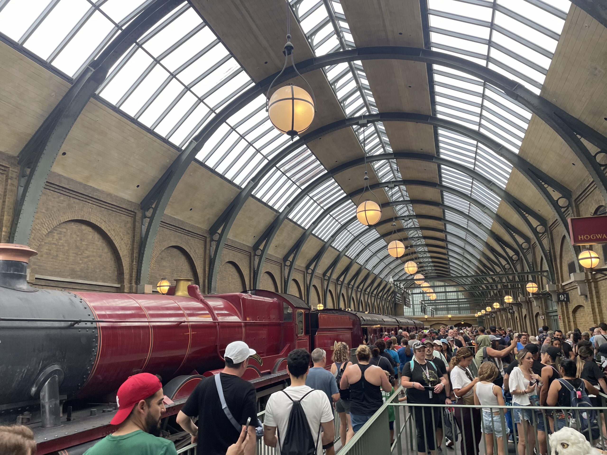 The scarlet Hogwarts Express steam train arriving at King's Cross Station in The Wizarding World of Harry Potter.