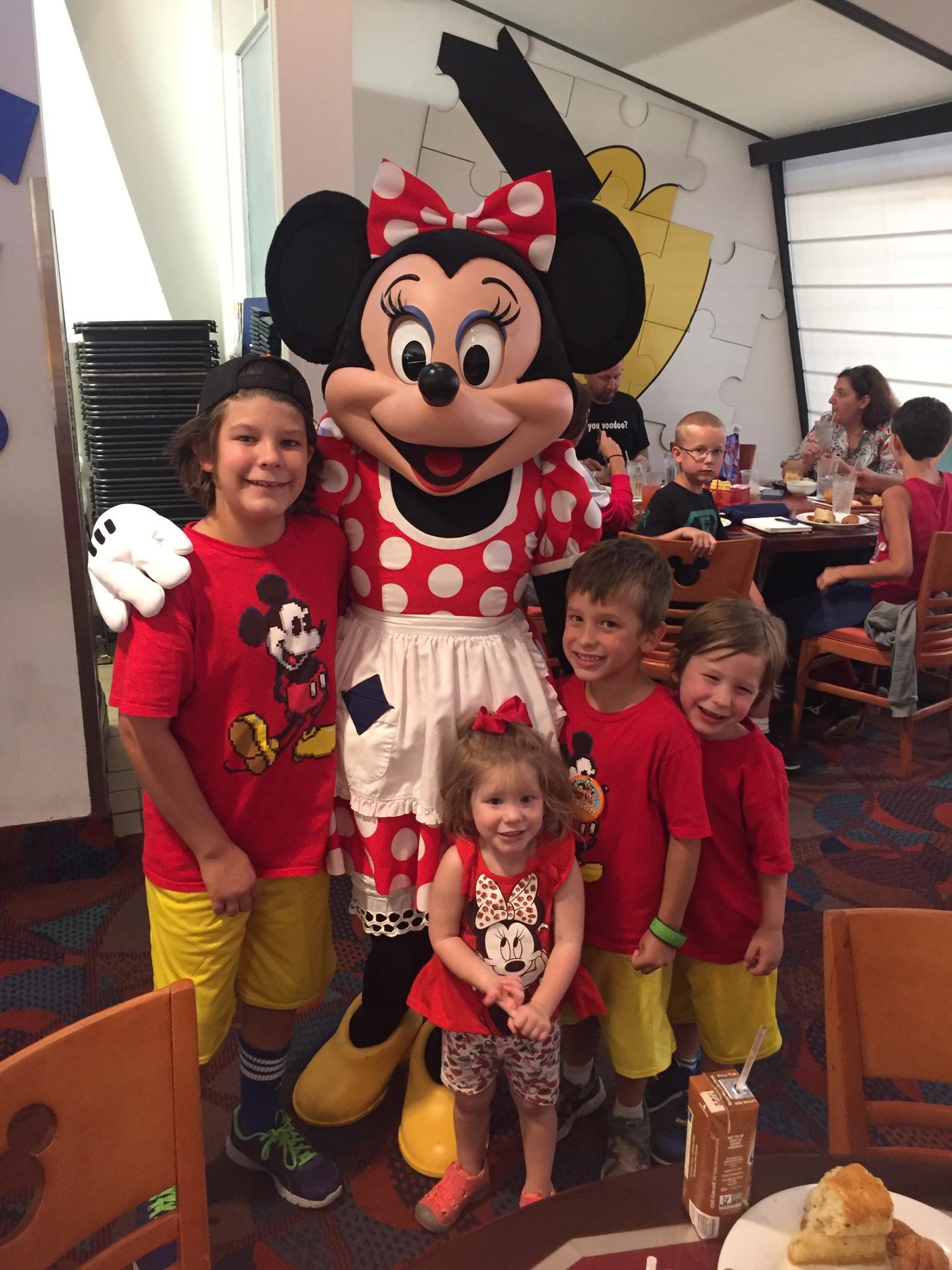 Four smiling children posing with Minnie Mouse during a character meet and greet at Walt Disney World Resort.