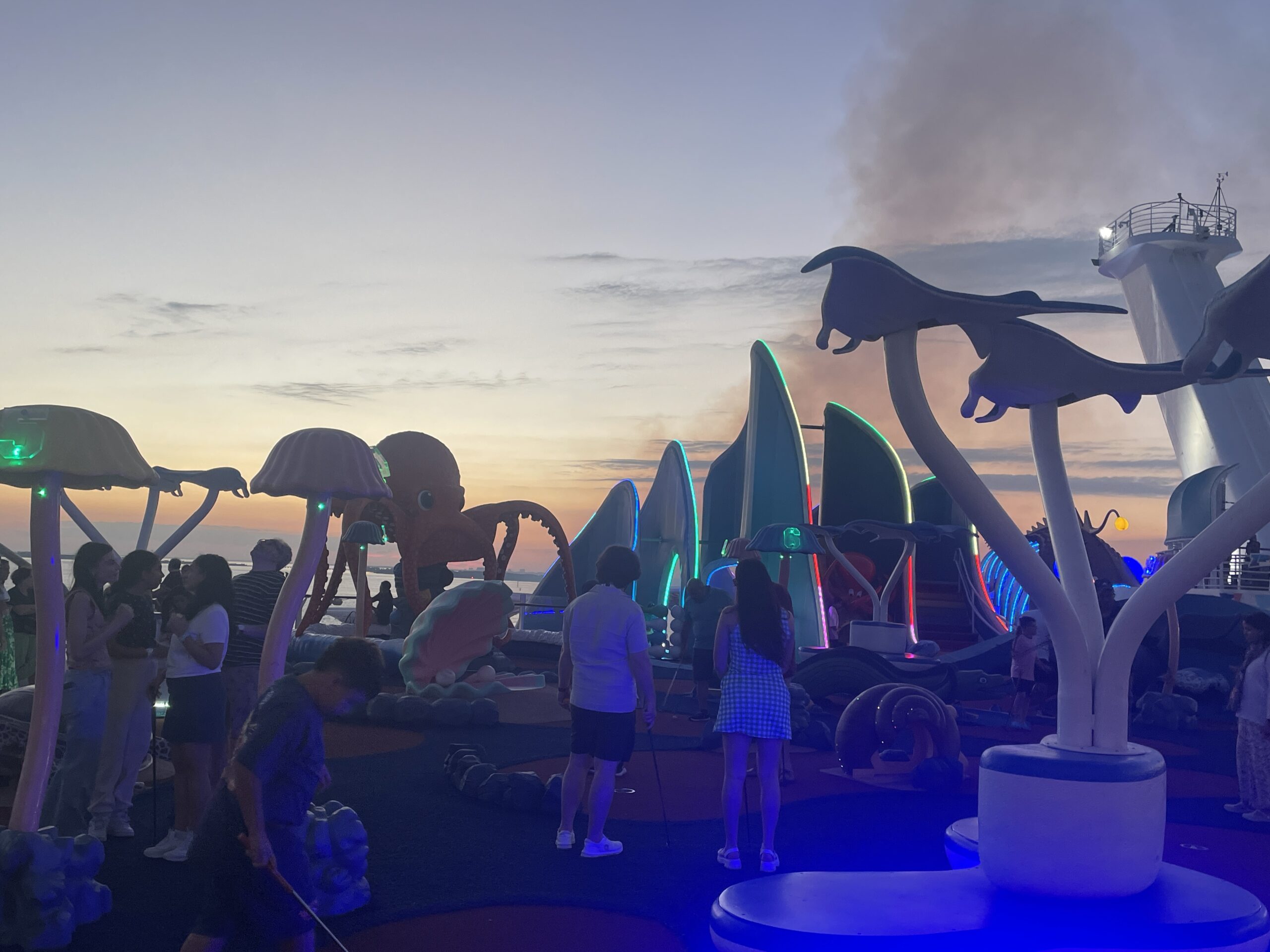 Children playing mini golf at the Wonder Playscape on Wonder of the Seas, featuring an underwater-themed outdoor climbing area and slides for kids.