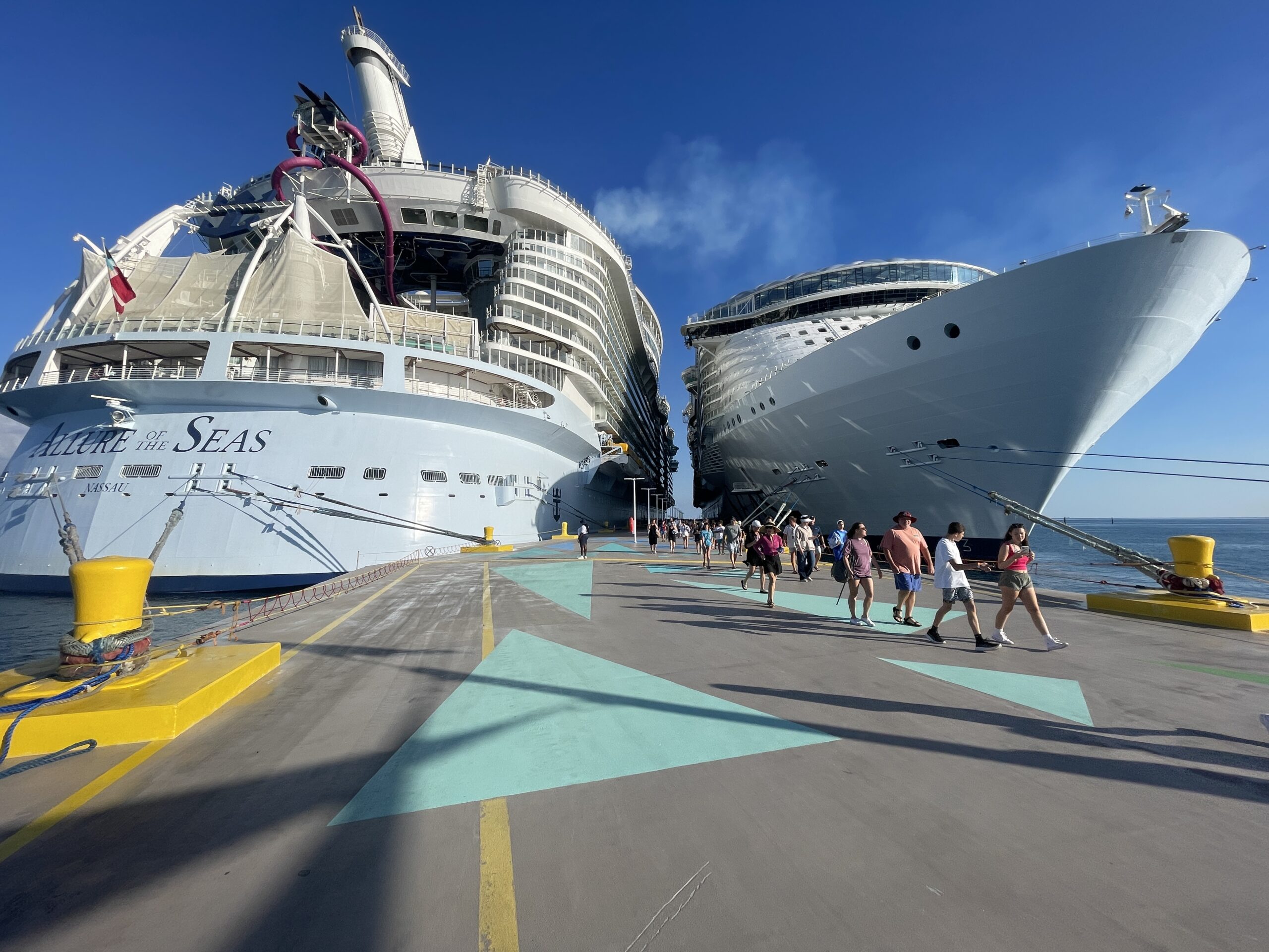 Two Royal Caribbean cruise ships docked at the Perfect Day at CocoCay pier in the Bahamas under a clear blue sky.