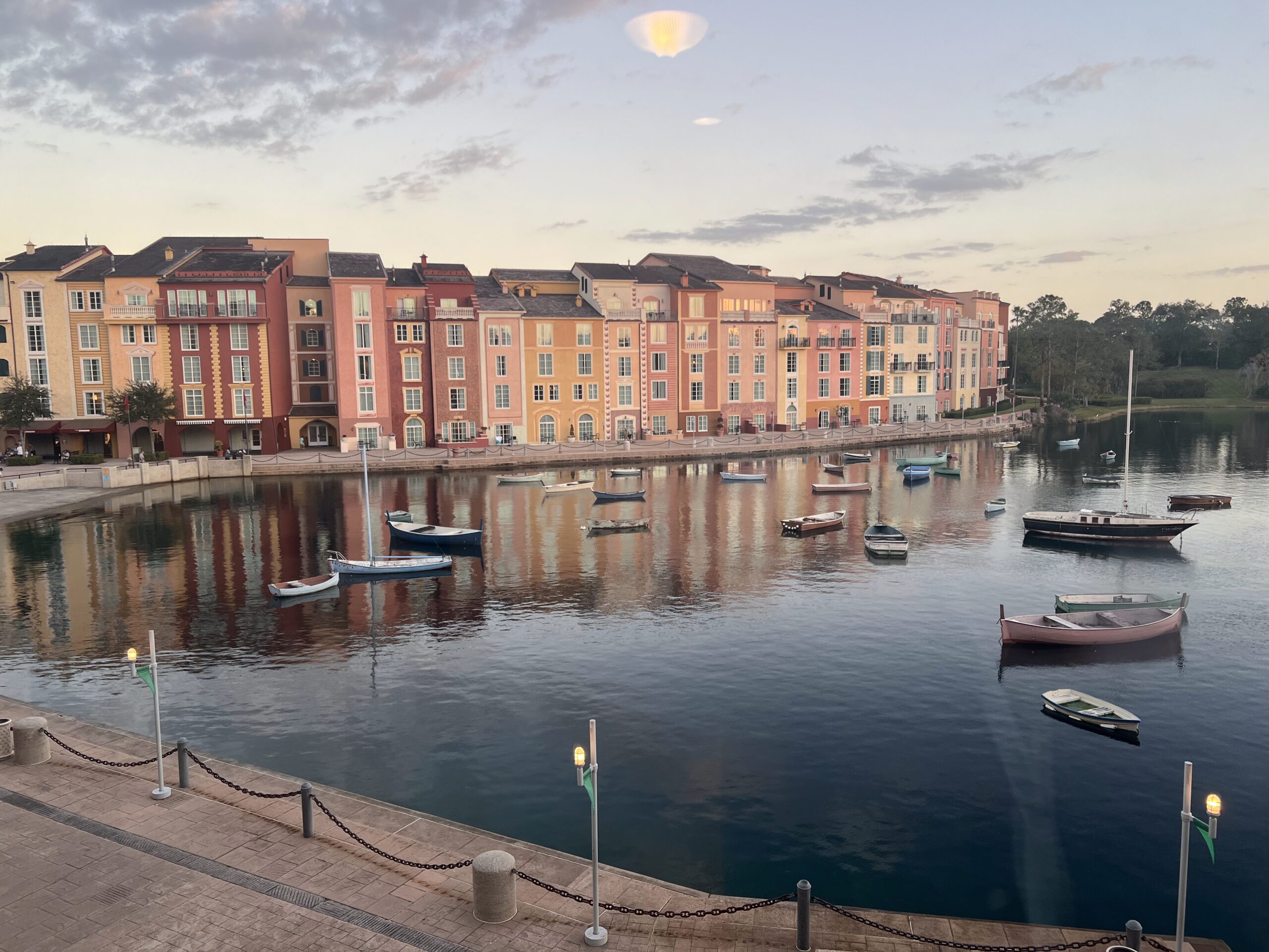 The picturesque Italian-inspired harbor at Universal's Portofino Bay Resort, featuring sun-splashed Mediterranean architecture and colorful buildings reflected in the sparkling blue water.