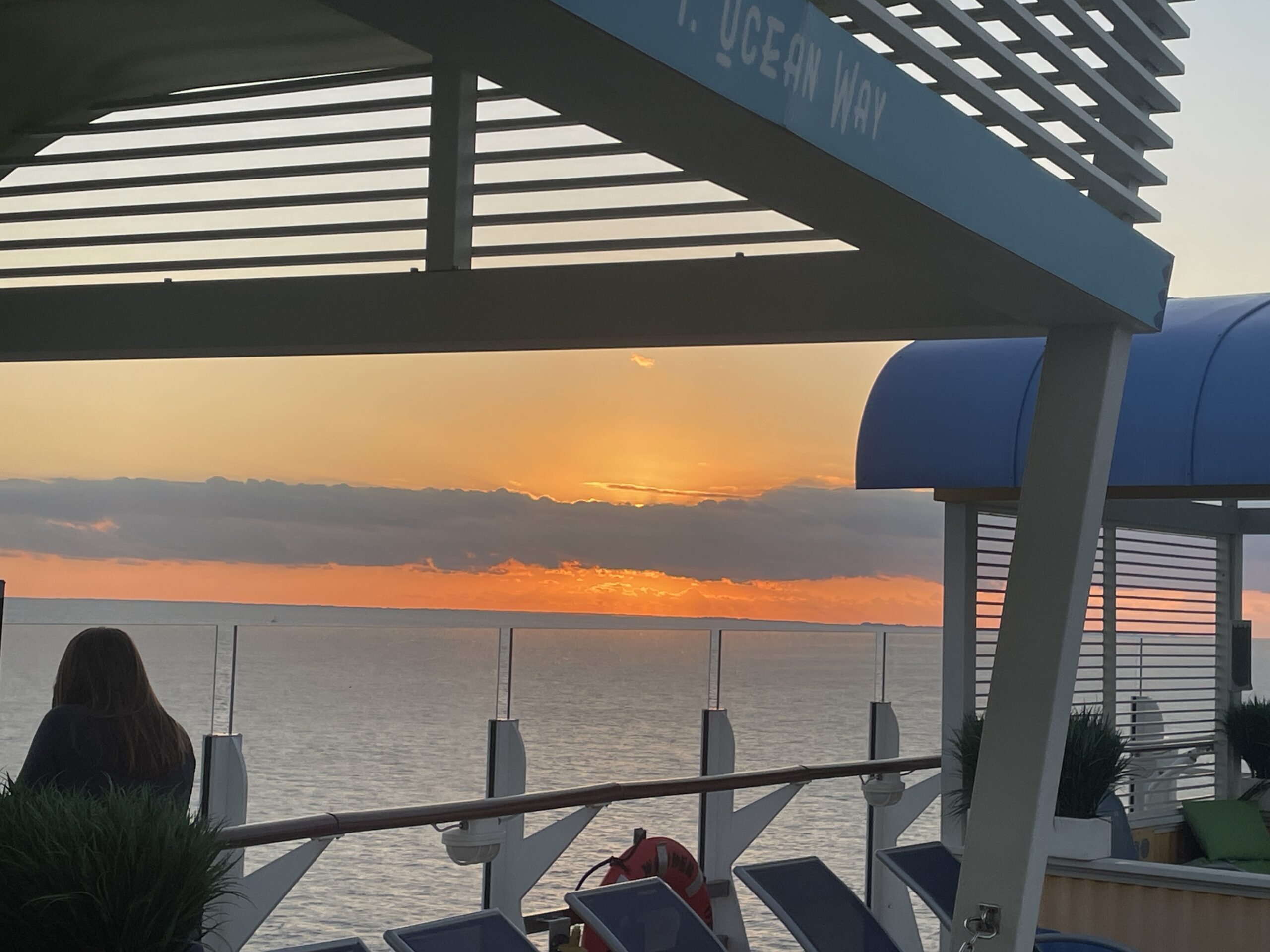 A woman enjoying the sunrise from the deck of a cruise ship