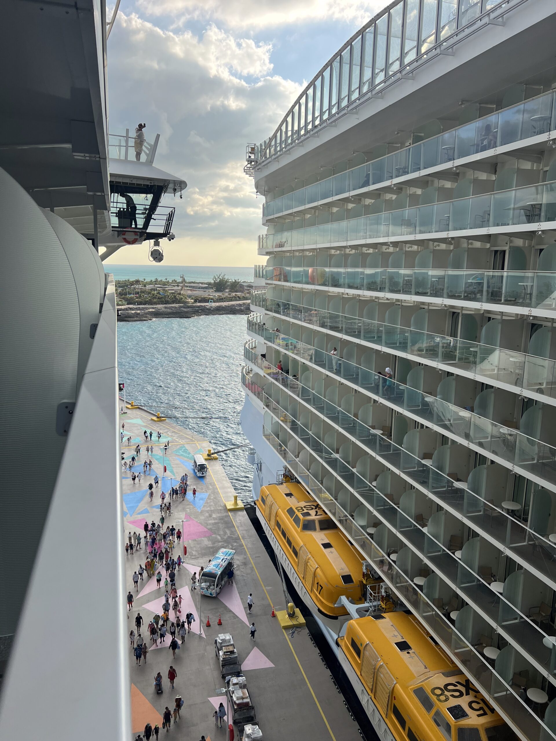 Close-up view of tiered ocean-view balconies on a Royal Caribbean ship as seen from a neighboring balcony, highlighting the privacy dividers and glass railings of different cabin categories.