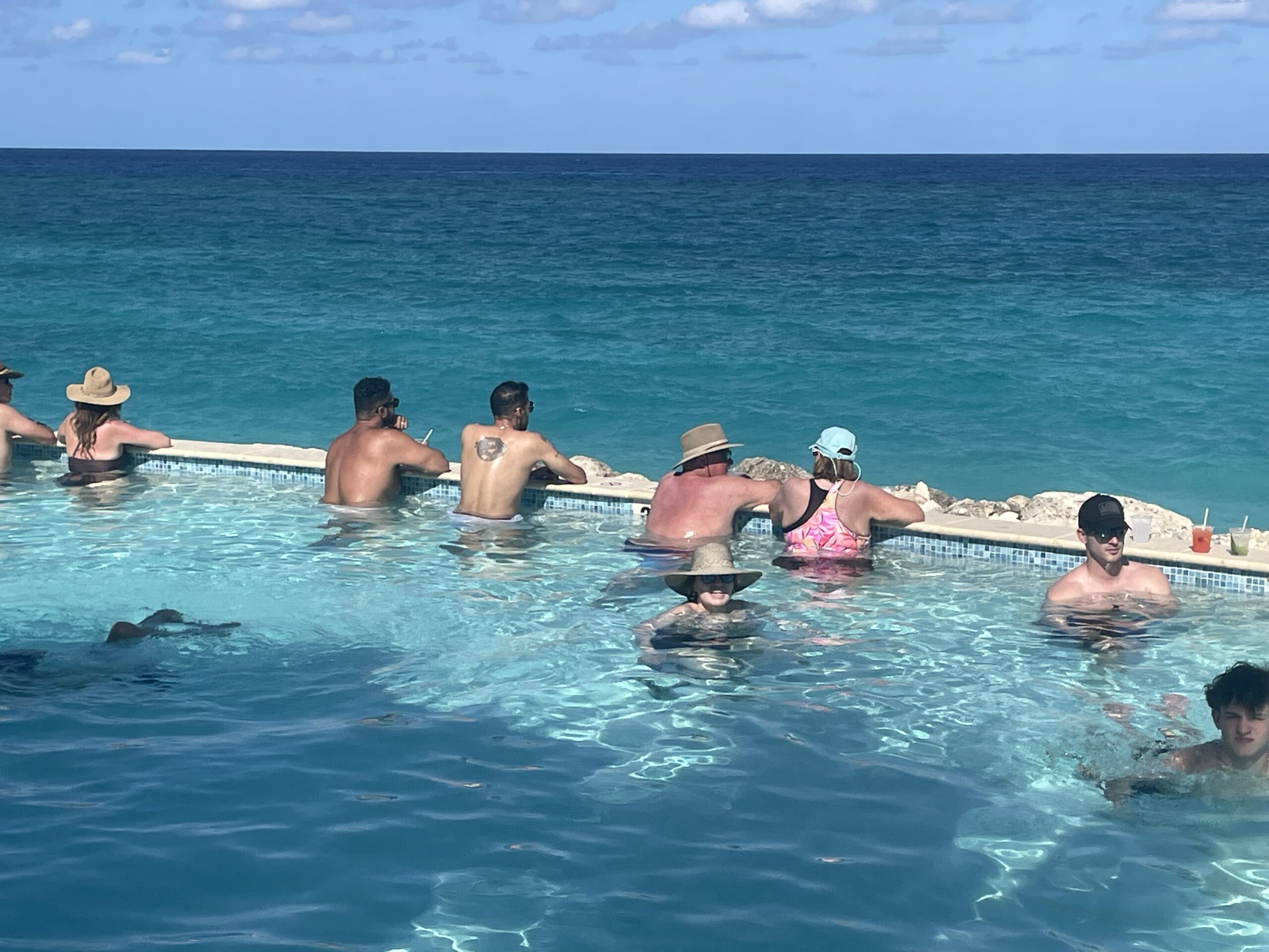 People enjoying a pool overlooking the ocean on Paradise Island