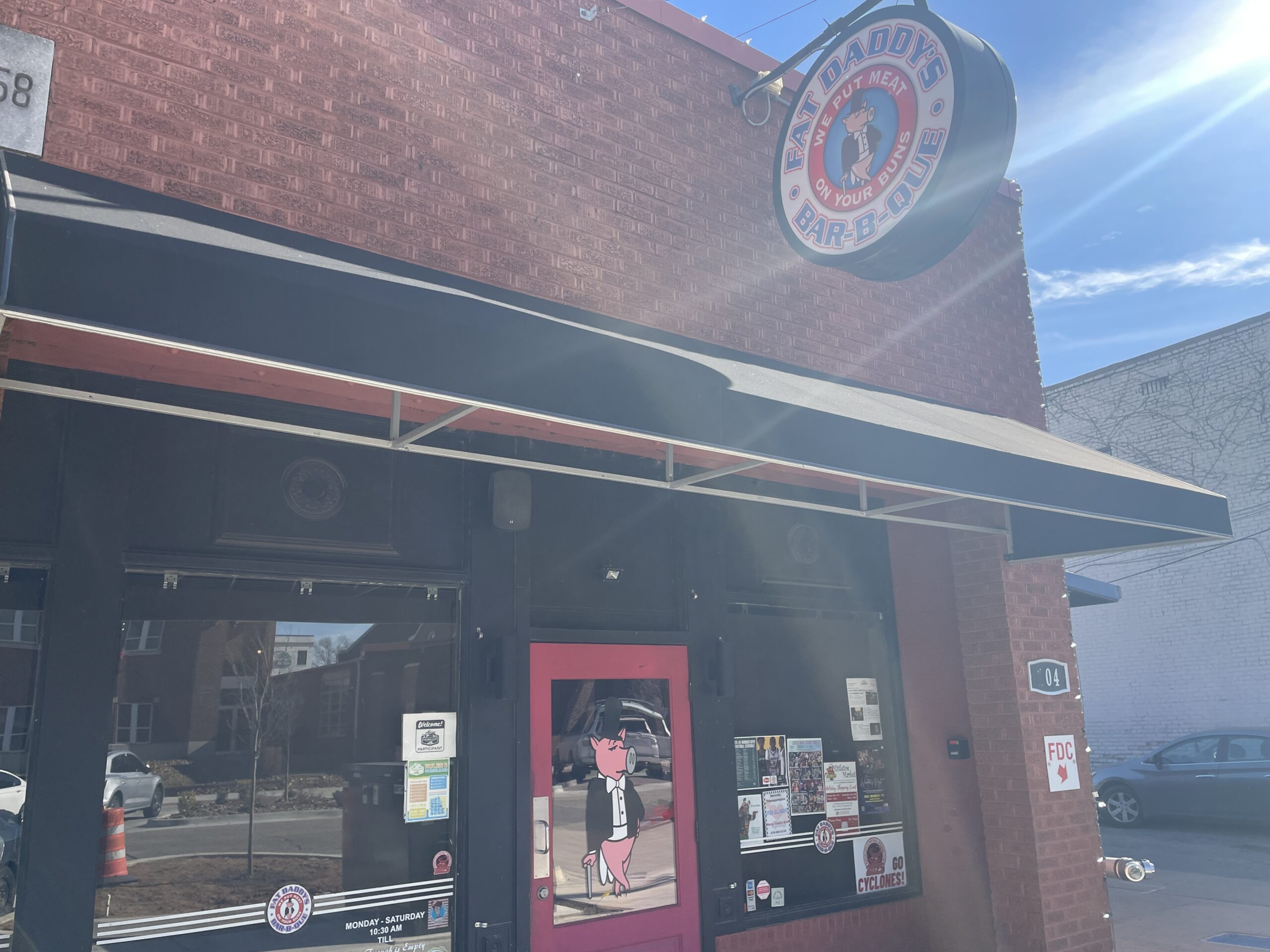 The rustic brick exterior and storefront of Fat Daddy's Bar-B-Que in downtown Russellville, Arkansas, a top-rated local BBQ restaurant in the River Valley.