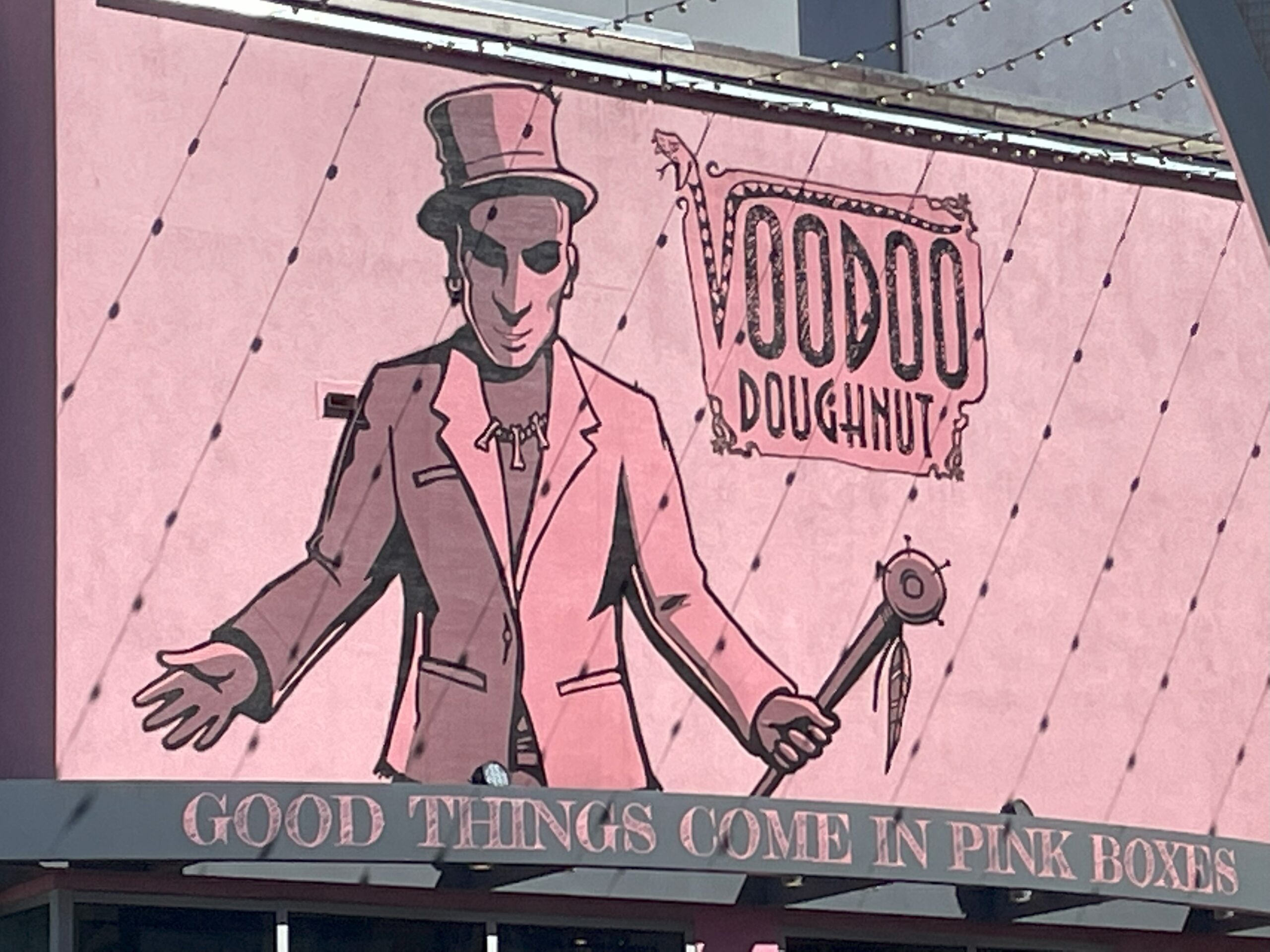 A picture of the pink Voodoo Doughnut sign in the City Walk of Universal Studios Orlando