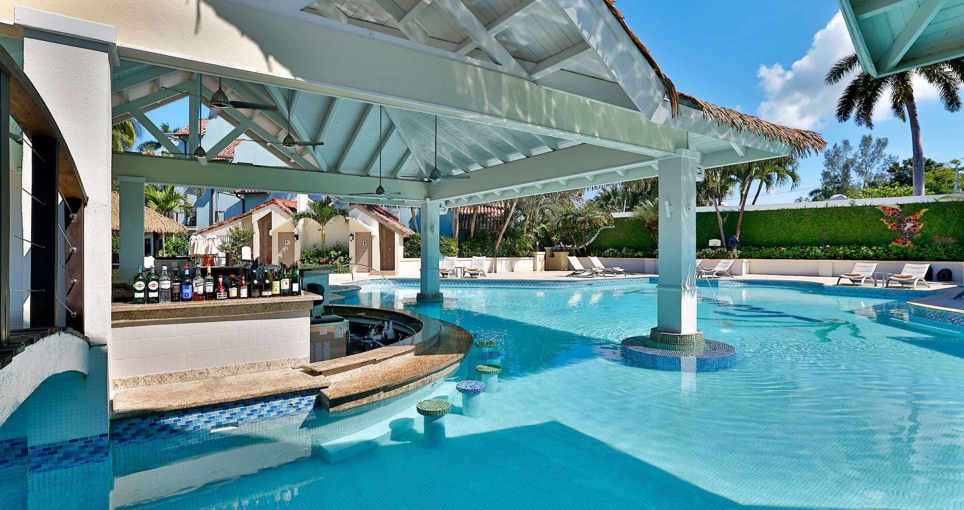 Sandals Resorts swim-up bar with premium spirits and thatched roof architecture in a crystal-clear lagoon pool.